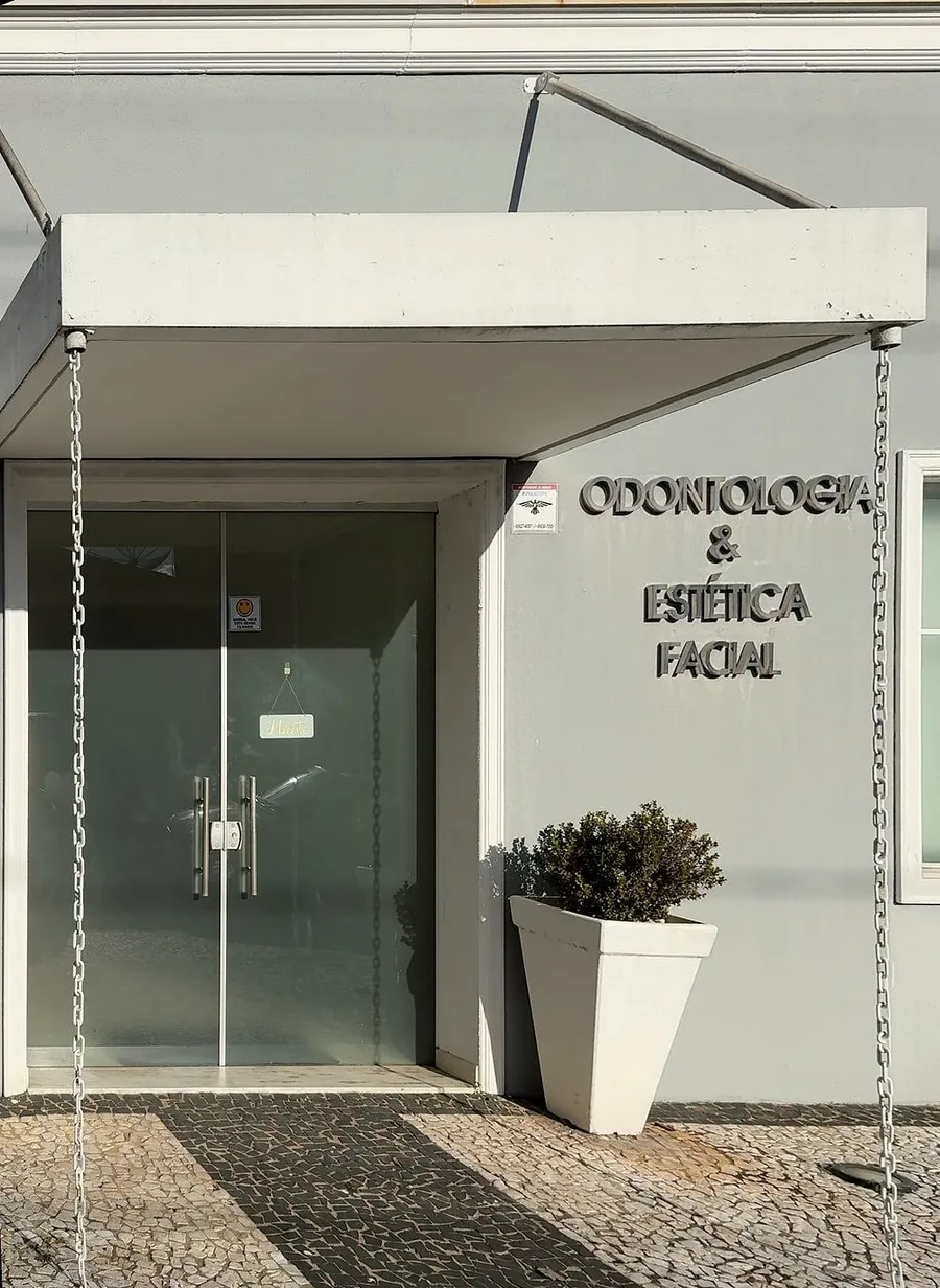 Entrada da clínica na Rua Prudente de Moraes, 498, com o toldo, a porta de vidro e o letreiro Odontologia e Estética Facial
