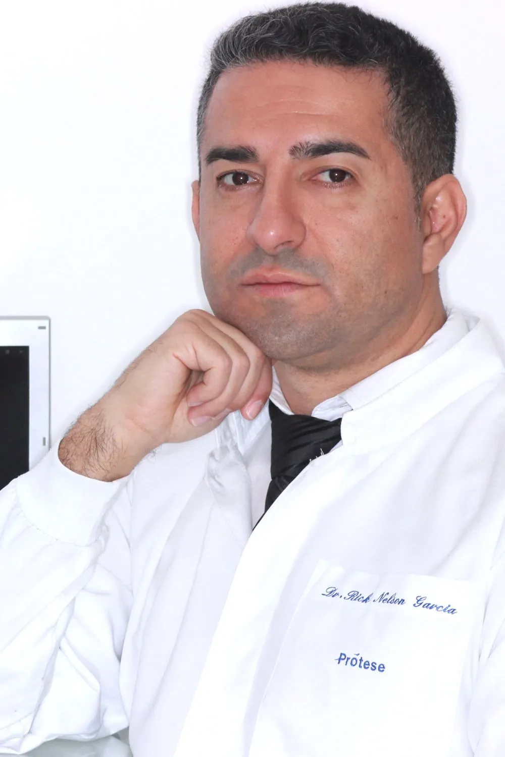 Dr. Rick Nelson Garcia, de jaleco branco, com a mão no queixo